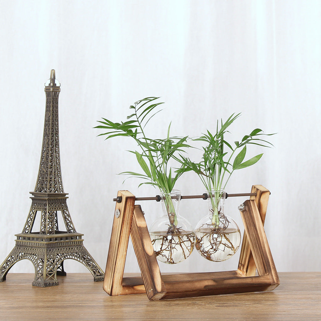 Cavira high borosilicate glass ball vase with retro wooden rack, used as a decorative planter or propagation station on a desktop.