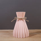 Minimalist paper vase with twine detail by Cavira, showcasing a creative plastic flower arrangement for home decor.
