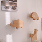 Wooden animal shape wall hooks featuring giraffe, hippo, lion, rabbit, and elephant for kids' rooms and nurseries by Cavira.