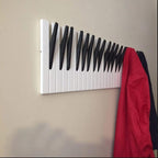 Wooden piano keyboard wall hook by Cavira in small, medium, and large sizes, mounted on a wall as creative decor for entryways or music rooms.