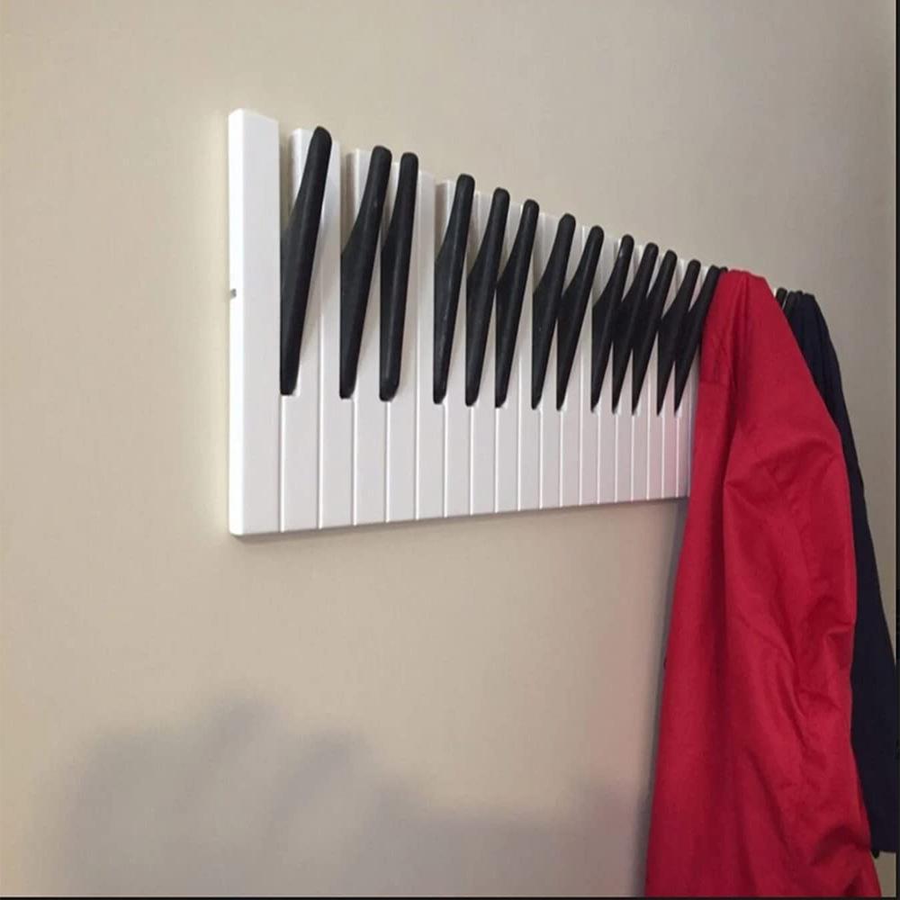 Wooden piano keyboard wall hook by Cavira in small, medium, and large sizes, mounted on a wall as creative decor for entryways or music rooms.