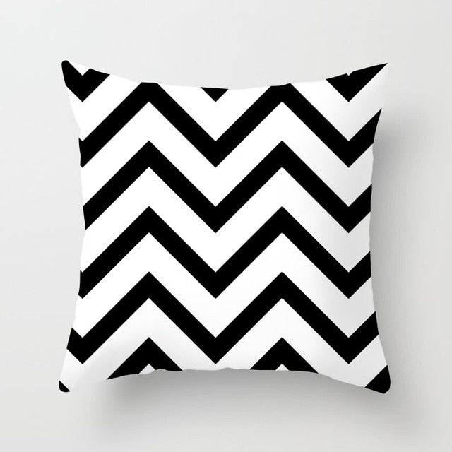 Black, white, and grey geometric jacquard knitted cushion cover by Cavira on a sofa, showcasing modern home decor style.