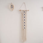 Handwoven cotton rope evil eye wall hanging tapestry with tassels on beech wood rod, boho macramé décor for bedroom or living room.