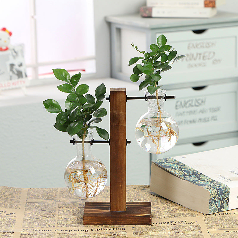 Transparent glass bottle vase with wooden frame by Cavira, ideal for desktop flower arrangements and home decor.