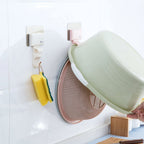 Pink and beige seamless wall-mounted washbasin hook rack by Cavira, made of ABS, punch-free bathroom basin hanger, installed on a wall.
